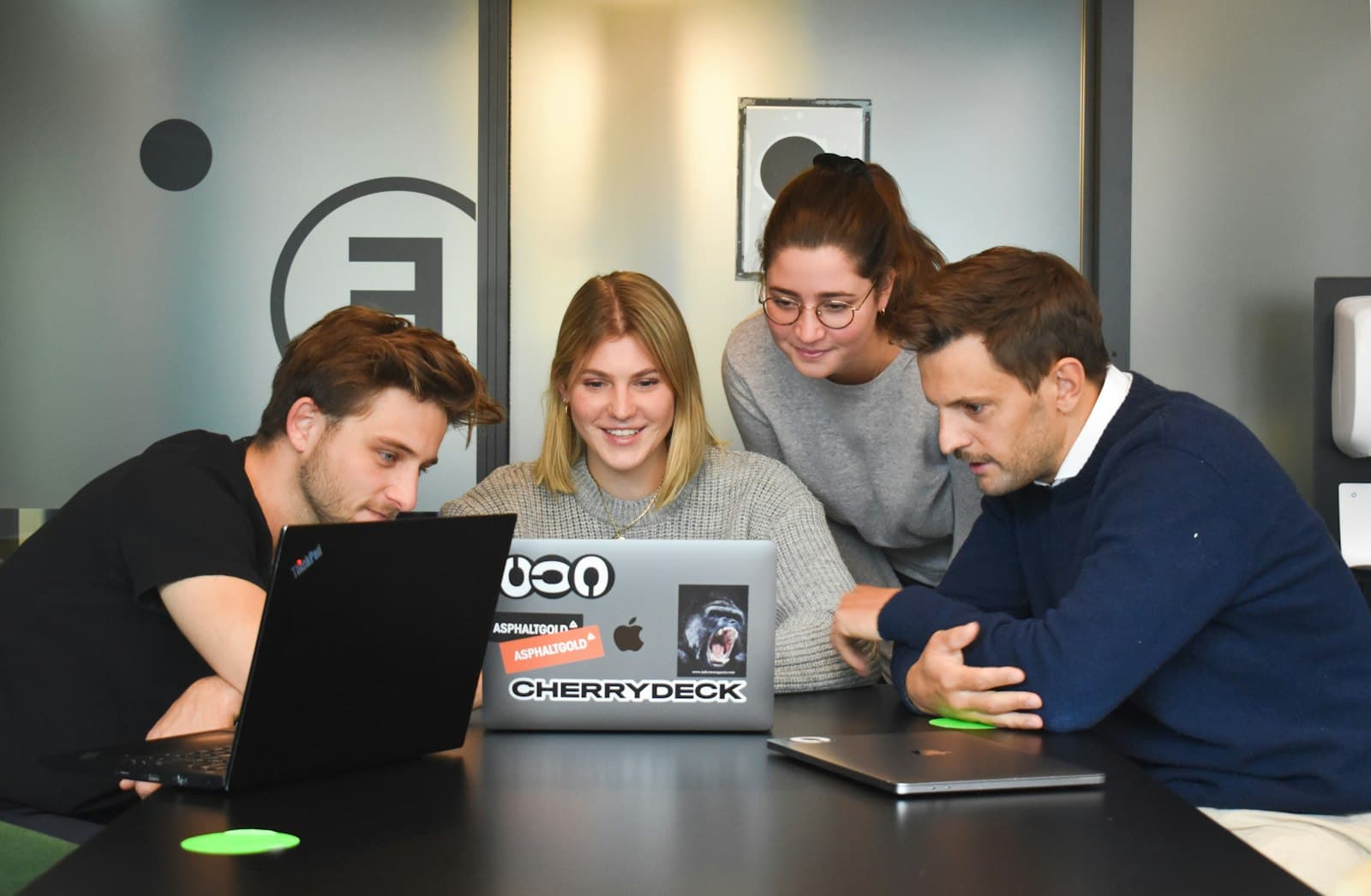 Four people collaborating around a laptop